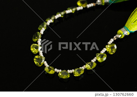 黒背景に映えるペリドットとパールのブリオレットカットルース 130762660