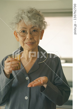 起床時に薬を飲む高齢者 130762700