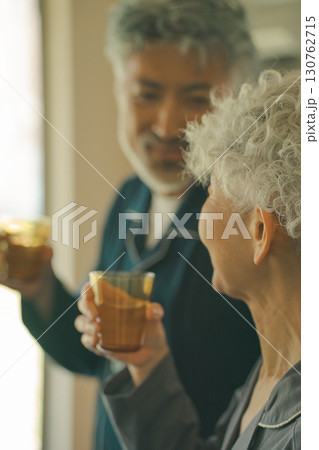 朝、水を飲む高齢夫婦 130762715
