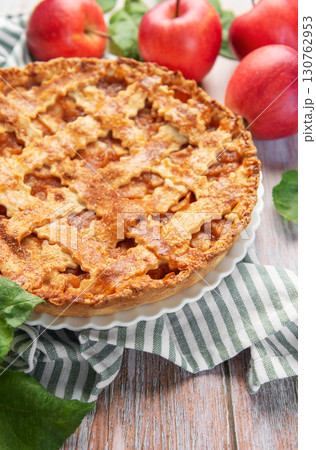 Freshly baked apple pie with red apples and leaves on rustic wooden table 130762953