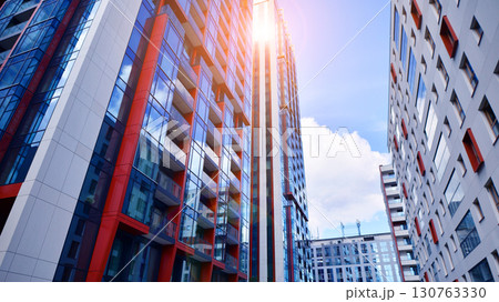 Exterior of a high modern multi-story apartment building - facade, windows and balconies. Timeless glass facade. Modern urban living district. Exterior of a high modern multi-story apartment building - facade, windows and balconies. Timeless glass facade. Modern urban living district. 130763330