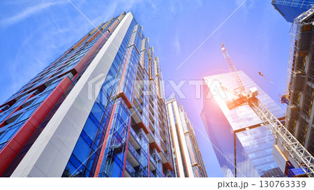 Exterior of a high modern multi-story apartment building - facade, windows and balconies. Timeless glass facade. Modern urban living district. Exterior of a high modern multi-story apartment building - facade, windows and balconies. Timeless glass facade. Modern urban living district. 130763339