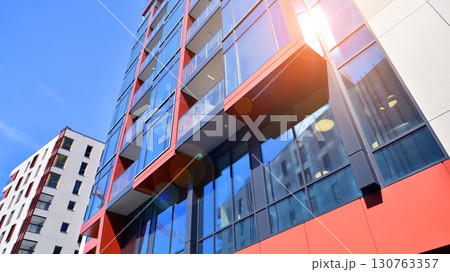 Exterior of a high modern multi-story apartment building - facade, windows and balconies. Timeless glass facade. Modern urban living district. 130763357