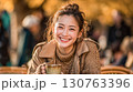 黄葉の街並みでコーヒーを楽しむ女性 130763396