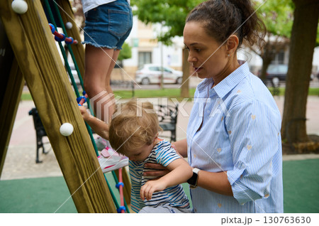 Mother Supporting Her Child on a Playground Adventure Outdoors Mother Supporting Her Child on a Playground Adventure Outdoors 130763630