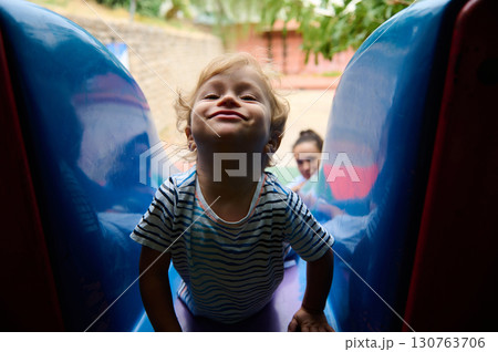 Child Playing on a Slide at an Outdoor Playground Child Playing on a Slide at an Outdoor Playground 130763706