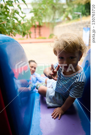 Child Enjoying Outdoor Playground Slide with Parent in a Sunny Park Setting Child Enjoying Outdoor Playground Slide with Parent in a Sunny Park Setting 130763710