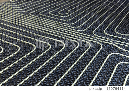 Plastic pipes for underfloor heating system installed over black insulation sheets in a new building Plastic pipes for underfloor heating system installed over black insulation sheets in a new building 130764114