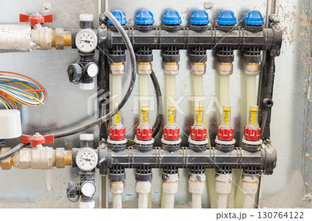 Pipes and valves for hot and cold water in heating and water supply system in boiler room closeup 130764122
