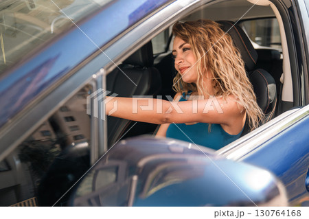 Young Blonde Woman Enjoying and Smiling in Blue Car 130764168