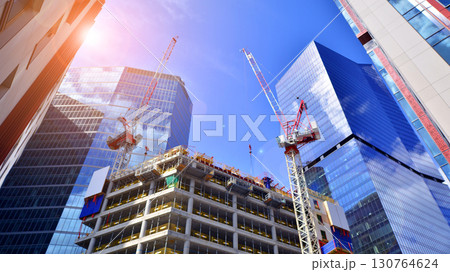 Crane on the construction site in a site surrounded by the high buildings. Office building under construction in the vicinity of high apartment buildings and office building. Crane on the construction site in a site surrounded by the high buildings. Office building under construction in the vicinity of high apartment buildings and office building. 130764624