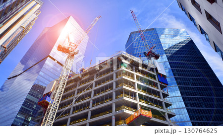Crane on the construction site in a site surrounded by the high buildings. Office building under construction in the vicinity of high apartment buildings and office building. 130764625