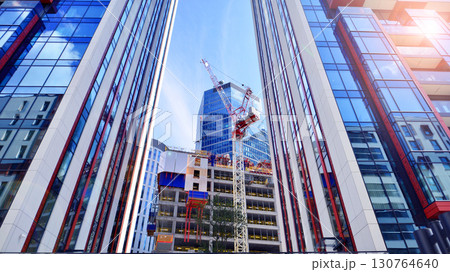 Crane on the construction site in a site surrounded by the high buildings. Office building under construction in the vicinity of high apartment buildings and office building. Crane on the construction site in a site surrounded by the high buildings. Office building under construction in the vicinity of high apartment buildings and office building. 130764640