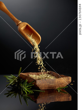 Dry rosemary are poured into a wooden bowl. Dry rosemary are poured into a wooden bowl. 130764844