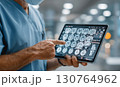 Medical doctor wearing surgical mask analyzing brain mri scan images on tablet computer 130764962