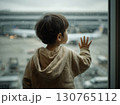 Toddler watching airplane taking off from airport window on rainy day 130765112