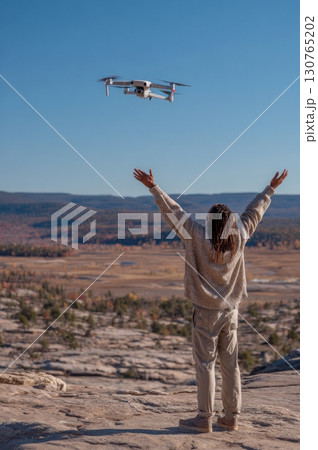 Videographer launching drone with open arms in desert landscape 130765202