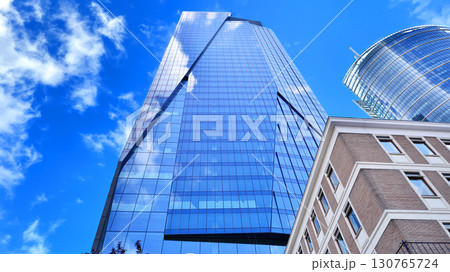 Modern sustainable glass office buildings. Exterior view of corporate headquarters glass buildings architecture.Glass windows in energy-efficient buildings. Financial business center buildings. Modern sustainable glass office buildings. Exterior view of corporate headquarters glass buildings architecture.Glass windows in energy-efficient buildings. Financial business center buildings. 130765724