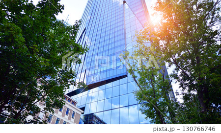 Sustainable glass office building with trees for reducing carbon dioxide. Eco-friendly building in modern city. Office with green environment. Corporate building reduce CO2. 130766746