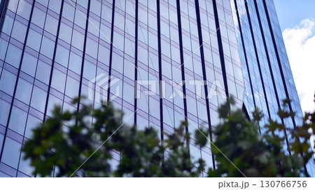 Sustainable glass office building with trees for reducing carbon dioxide. Eco-friendly building in modern city. Office with green environment. Corporate building reduce CO2. Sustainable glass office building with trees for reducing carbon dioxide. Eco-friendly building in modern city. Office with green environment. Corporate building reduce CO2. 130766756