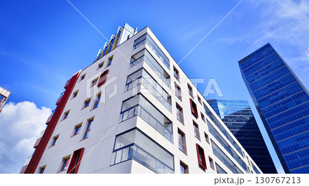 View of an modern apartment building standing next to a new modern office building with a glass facade. 130767213