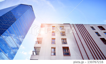View of an modern apartment building standing next to a new modern office building with a glass facade. View of an modern apartment building standing next to a new modern office building with a glass facade. 130767216