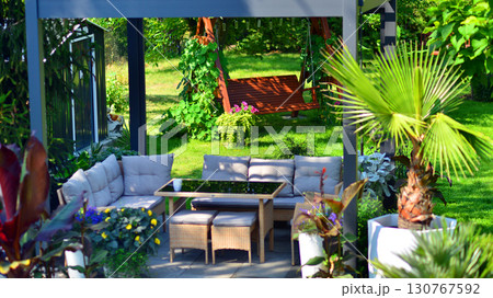 Modern aluminum pergola with stylish garden furniture in a beautiful garden. 130767592