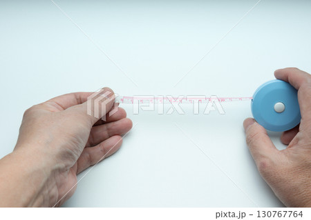 巻き尺を引っ張り出した両手 130767764