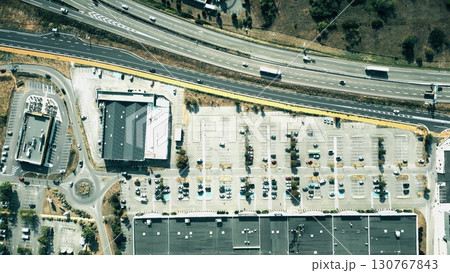 Aerial shot of a commercial area in Valence, France. Parking lots, shops, and nearby highway traffic are visible from above 130767843