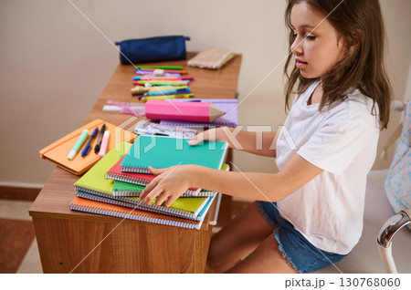 Young Girl Organizing School Supplies on a Wooden Desk at Home Young Girl Organizing School Supplies on a Wooden Desk at Home 130768060