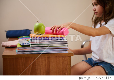 Young Student Organizing School Supplies at Desk for Productive Study Session Young Student Organizing School Supplies at Desk for Productive Study Session 130768117