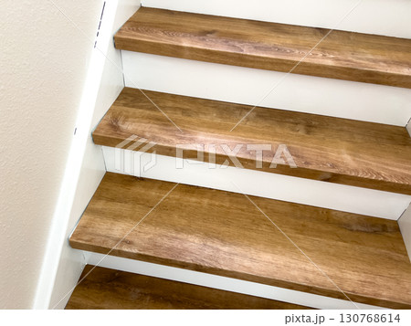 Closeup view of a residential staircase with clean wood treads and bright white risers. The stairs are well lit, creating a fresh and tidy visual style. Closeup view of a residential staircase with clean wood treads and bright white risers. The stairs are well lit, creating a fresh and tidy visual style. 130768614