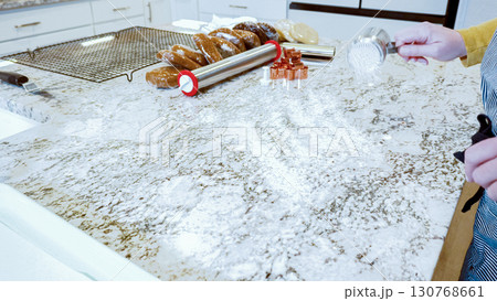 Using an adjustable rolling pin to roll out gingerbread cookie dough on the elegant marble counter in a modern kitchen, getting ready for festive holiday baking. 130768661