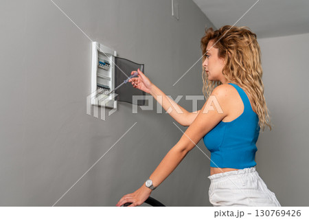 Young Woman Fixing Electrical Fuse Box with Screwdriver 130769426