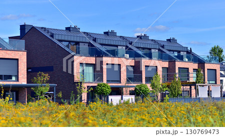 Harmony with nature, eco architecture. Terraced single family homes in newly developed housing estate. The real estate market in the suburbs with lush greenery surrounding. Harmony with nature, eco architecture. Terraced single family homes in newly developed housing estate. The real estate market in the suburbs with lush greenery surrounding. 130769473