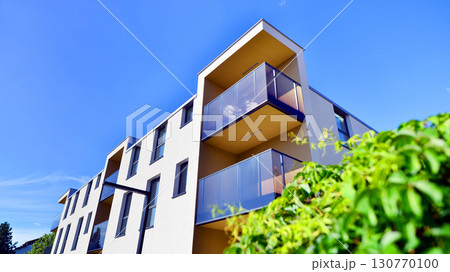 European residential architecture harmonizing with nature. Eco-friendly living in city with greens. Eco apartment building saving energy and fresh air concept.  130770100