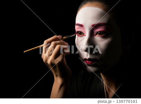 Japanese woman in a kimono applying traditional kabuki or geisha makeup with a brush 130770181