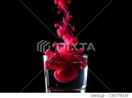 Red ink or paint dropping into a glass of water creating an abstract cloud on a black background 130770185