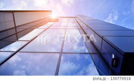 Modern office building with glass facade. Transparent glass wall of office building. Reflection of the blue sky on the facade of the building. Modern office building with glass facade. Transparent glass wall of office building. Reflection of the blue sky on the facade of the building. 130770918