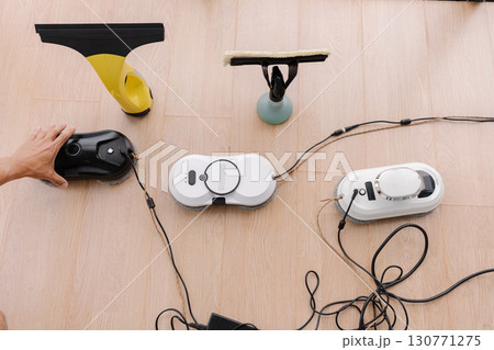 Top view of window cleaning robots, cordless window cleaner and window cleaning mop sitting on ledge, cables attached and ready for cleaning window, close-up, no people, nobody. 130771275