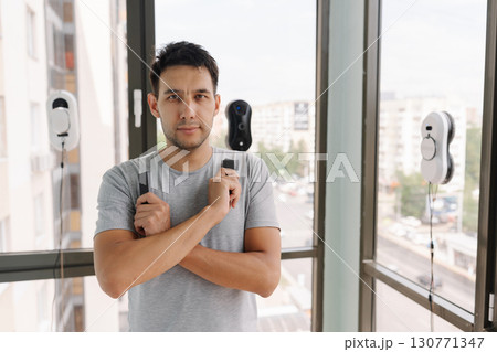 Portrait of confident window washer controlling robotic cleaning devices during high-rise exterior maintenance, showcasing advanced technological efficiency in urban environment, looking at camera 130771347