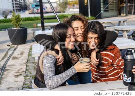 Latin american women sharing mate outdoors and embracing friendship 130771429