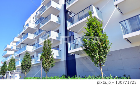 Modern apartment building with balconies and greenery. Beautiful view of real estate buildings in summer. Walking area with trees and grass. Modern residential buildings in the public green area. Modern apartment building with balconies and greenery. Beautiful view of real estate buildings in summer. Walking area with trees and grass. Modern residential buildings in the public green area. 130771725
