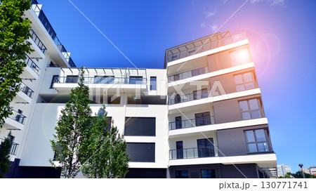 Modern apartment building with balconies and greenery. Beautiful view of real estate buildings in summer. Walking area with trees and grass. Modern residential buildings in the public green area. Modern apartment building with balconies and greenery. Beautiful view of real estate buildings in summer. Walking area with trees and grass. Modern residential buildings in the public green area. 130771741