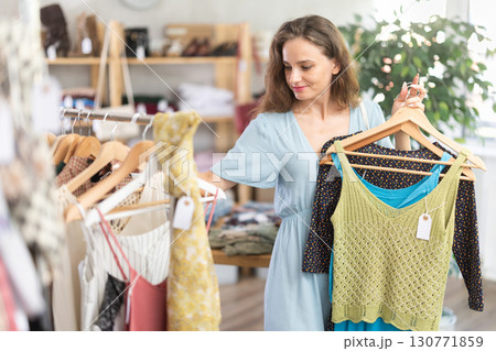 Young woman choosing tank tops in a store 130771859