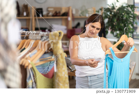 Latin woman customer turn over and choose something summer cloth in store, 130771909