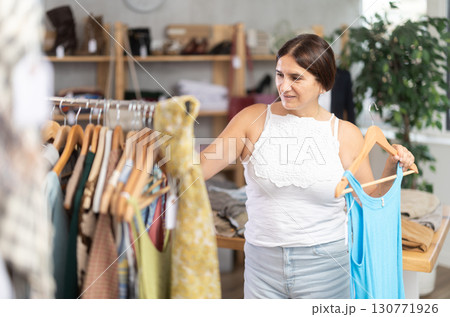 Latin woman customer turn over and choose something summer cloth in store, 130771926