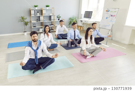 Business people meditating and having a rest in the office sitting on floor in Lotus pose 130771939