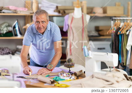 Senior man tailor draw dress pattern of product on paper 130772005