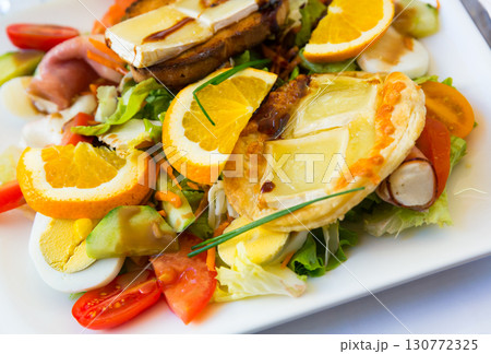 Salad from goat cheese, orrange, vegetables and honey at plate, dish of french cuisine Salad from goat cheese, orrange, vegetables and honey at plate, dish of french cuisine 130772325